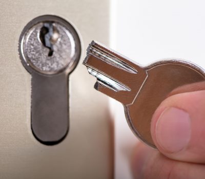 Close-up Of A Man Holding Broken Key Near Keyhole
